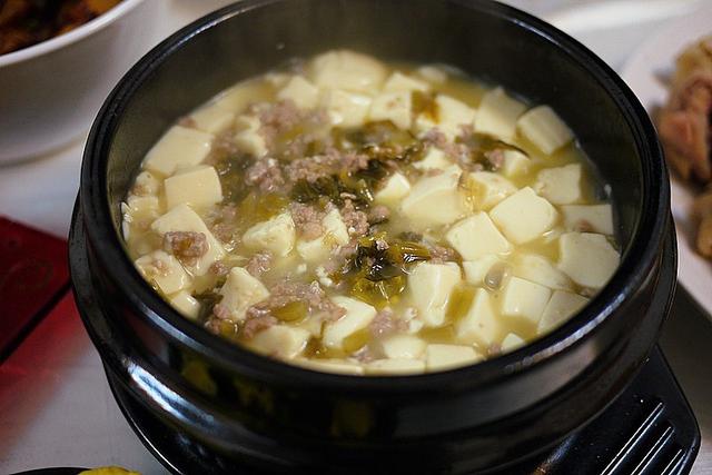 用料嫩豆腐;雪菜;肉末做法加熱石鍋,倒少許油,爆香姜蒜片,煸白肉末;加